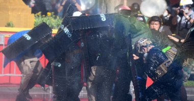 Anti-government protesters take cover as riot police spray them with a water cannon during a march toward Government House, demanding Thai Prime Minister Prayuth Chan-O-Cha's resignation, a mandatory vaccination policy and reform in the monarchy, Bangkok, Thailand, July 18, 2021. (Reuters Photo)