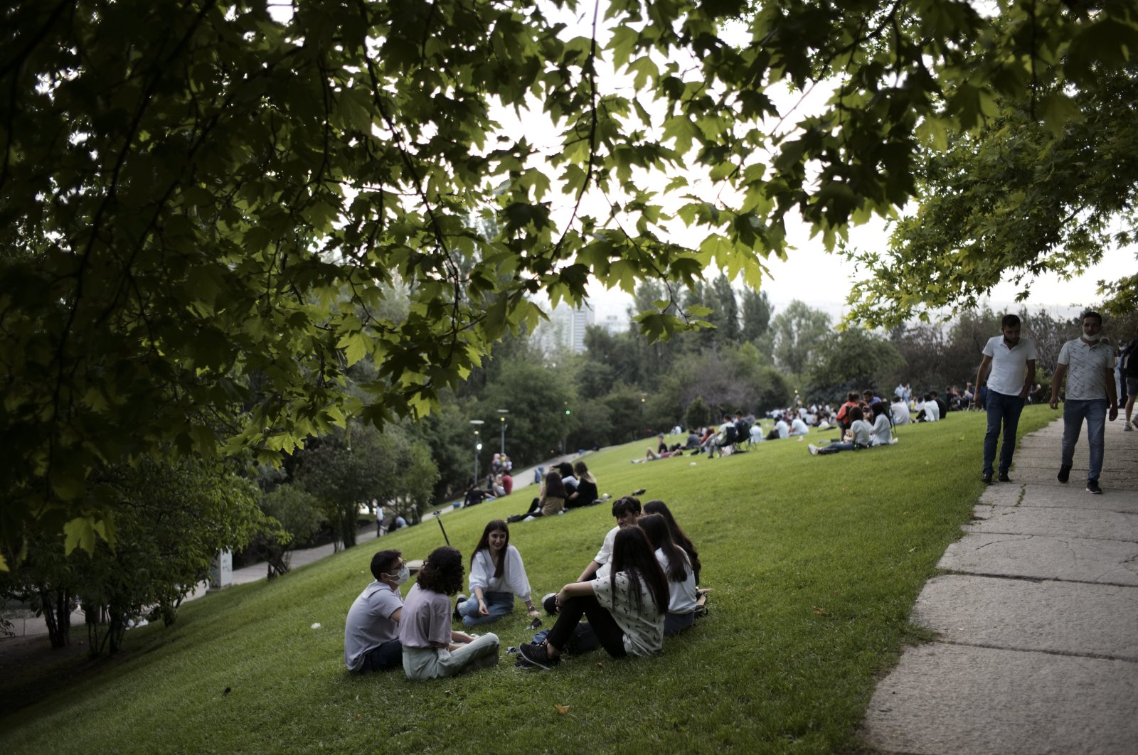 People sit in Seymenler Park in Ankara, Turkey, late Monday, June 28, 2021. (AP File Photo/Burhan Özbilici)
