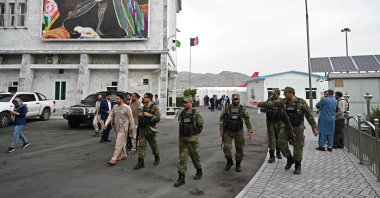 Security personnel walk past a poster of former Afghan President Hamid Karzai at the Hamid Karzai International Airport in Kabul, Afghanistan, July 16, 2021. (AFP Photo)