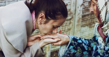 A young girl presents her bayram greeting by kissing the hand of an elder. (Shutterstock Photo)