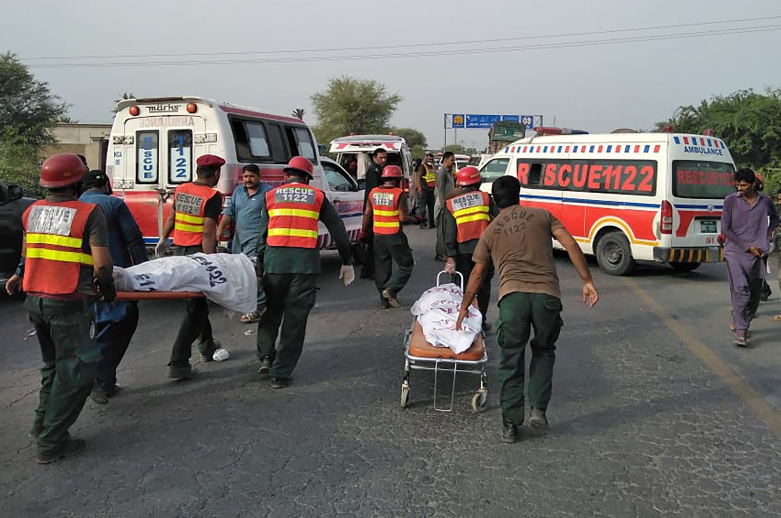 Rescue workers remove bodies at the site of a deadly bus accident near Dera Ghazi Khan, Pakistan, Monday, July 19, 2021. (Emergency Service Rescue 1122 via AP)