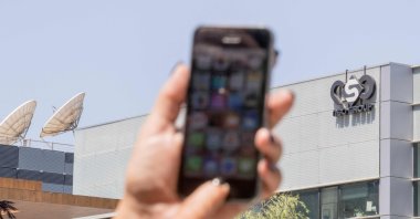 A woman uses her iPhone in front of the building housing the Israeli NSO group "Pegasus," in Herzliya, near Tel Aviv, Israel, Aug. 28, 2016. (AFP Photo)