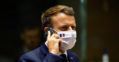 French President Emmanuel Macron speaks on his mobile phone during a round table meeting at an EU summit in Brussels, Belgium, July 20, 2020. (AP File Photo)