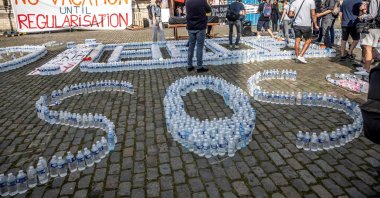 The words "help" and "SOS" are spelled with water bottles during a demonstration in front of the Saint John the Baptist at the Beguinage church, occupied by undocumented immigrants, Brussels, Belgium, July 19, 2021. (AFP Photo)