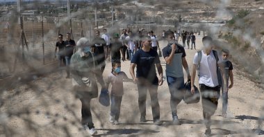 Palestinians cross into Israel through a damaged section in the Israeli separation fence, aiming for a day on the beach as they celebrate the second day of Eid al-Adha, in the West Bank village of Faroun, near Tulkarm, Palestine, July 21, 2021. (AP Photo)