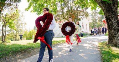 People carry wreaths of red roses on Utoya, Norway, during a memorial service on 22 July 2021, ten years after a right-wing extremist killed 77 people in twin attacks. (AFP Photo)