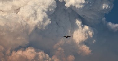 A firefighting aircraft returns to base amid massive plumes of smoke after dropping flame-retarding chemicals on the Bootleg Fire, as it expands to over 225,000 acres, in Bly, Oregon, U.S., July 15, 2021. (Reuters Photo)