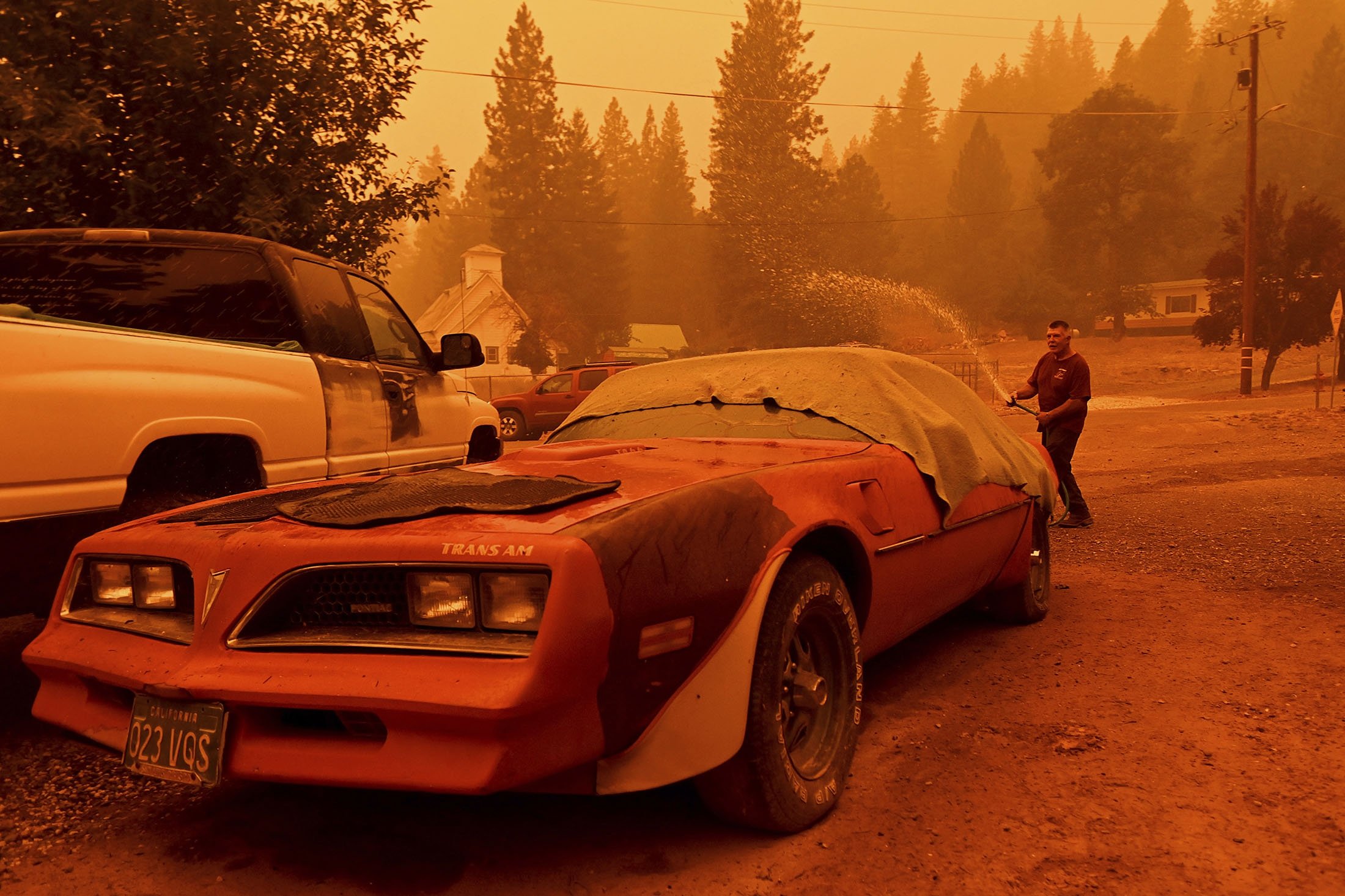 William Deal wets down his 1977 Trans Am as the Dixie Fire approaches Crescent Mills in Plumas County, California, U.S., July 24, 2021. (AP Photo)