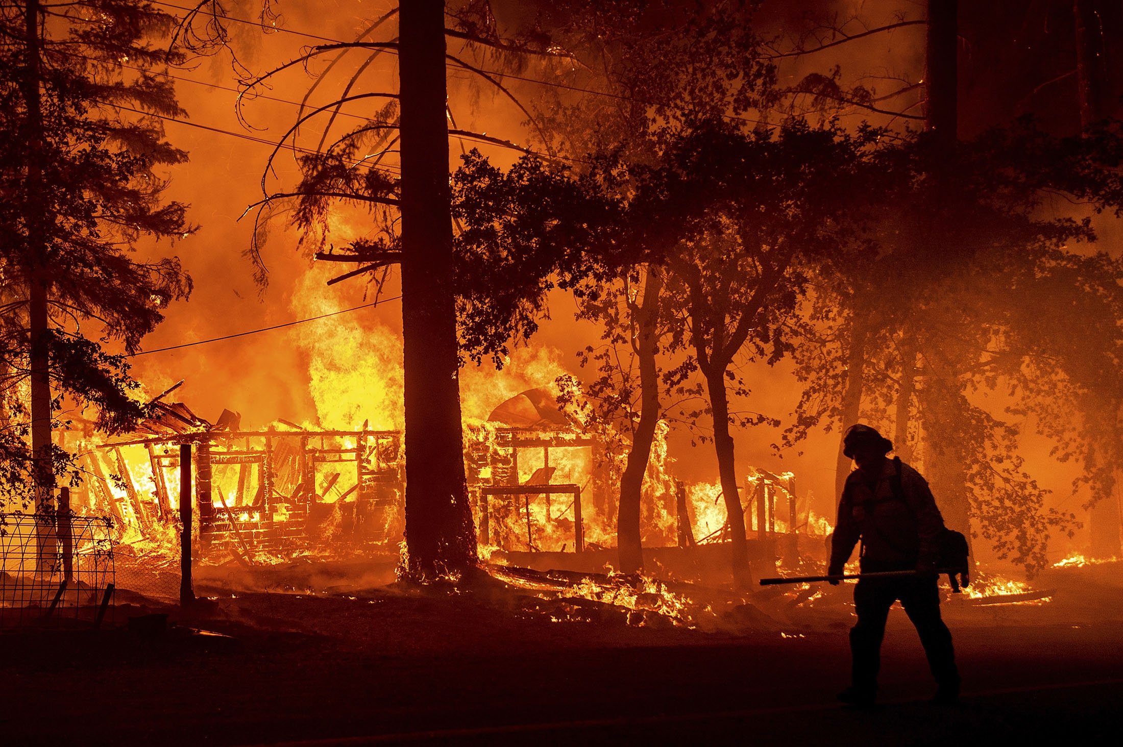 A firefighter passes a burning home as the Dixie Fire flares in Plumas County, California, U.S., July 24, 2021. (AP Photo)