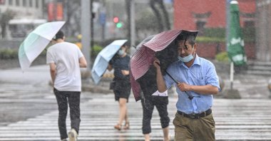 People cross the street in the wind and rain as Typhoon In-fa lashes the country's eastern coast, Ningbo, China, July 25, 2021. (AFP Photo)