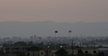 A Turkish military guard post with a Turkish flag (L) and Turkish Cypriot flag with Maraş (Varosha) in the background, prior to the Turkish President's visit to Turkish Cyprus, in Dherynia, TRNC, July 19, 2021. (AP Photo)