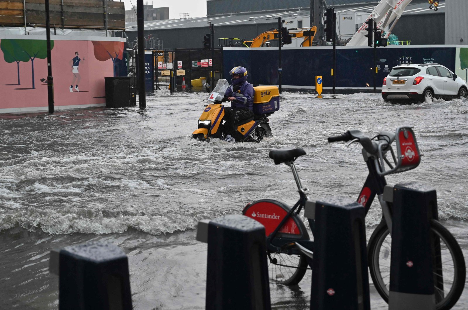 A motorcyclist rides through deep water on a flooded road in The Nine Elms district of London, England, July 25, 2021. (AFP Photo)
