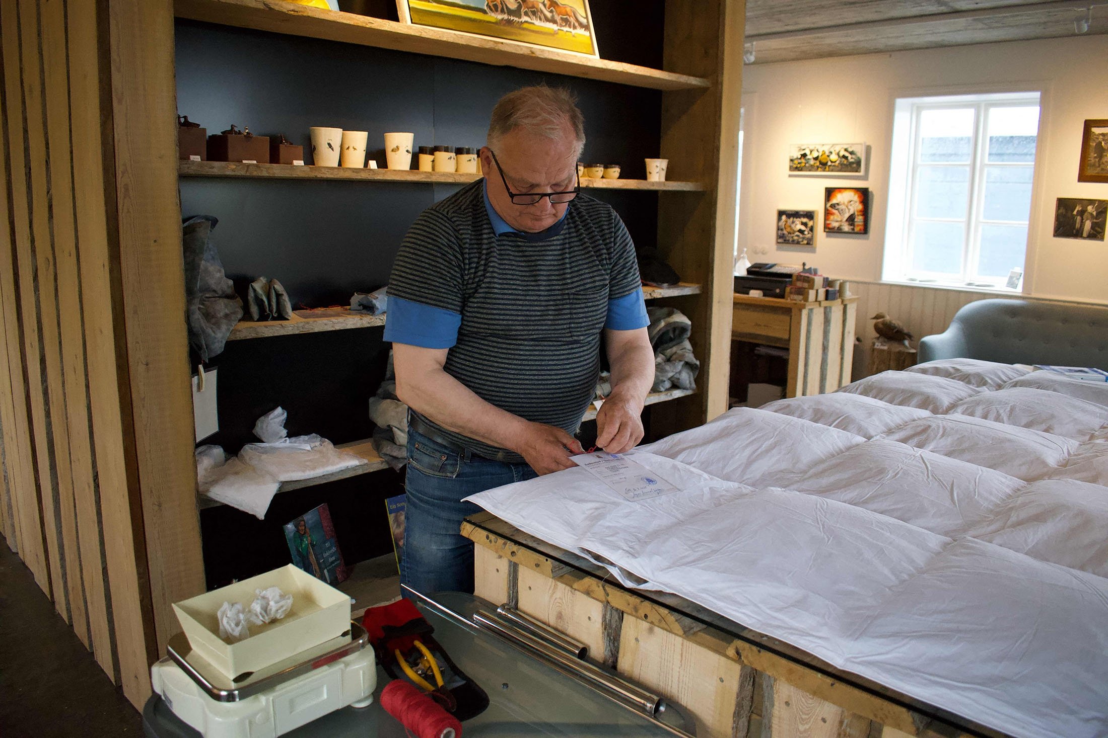Quality inspector Asgeir Jonsson puts a quality certificate on a recently made eiderdown duvet at the King Eider company in Stykkisholmur, Iceland, July 5, 2021. (AFP Photo)