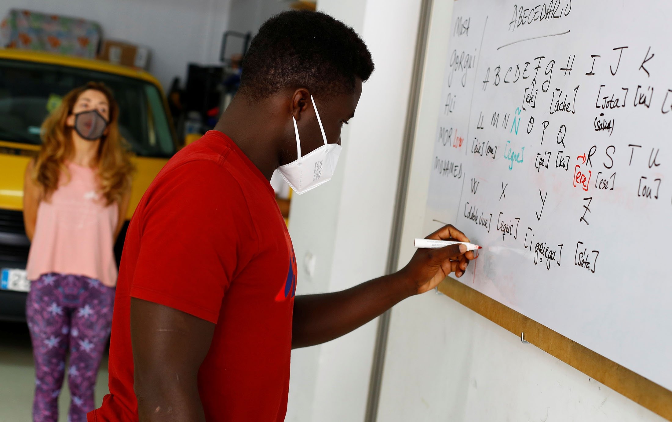 Ali Thiam (R), a migrant from Senegal, is taught Spanish by volunteer teacher Isabel Florido in Tito Martin