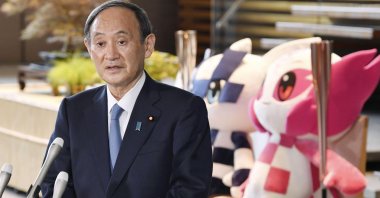 Japan's Prime Minister Yoshihide Suga speaks to the media in front of the Olympics mascots at the prime minister's office in Tokyo, July 1, 2021. (AP Photo)