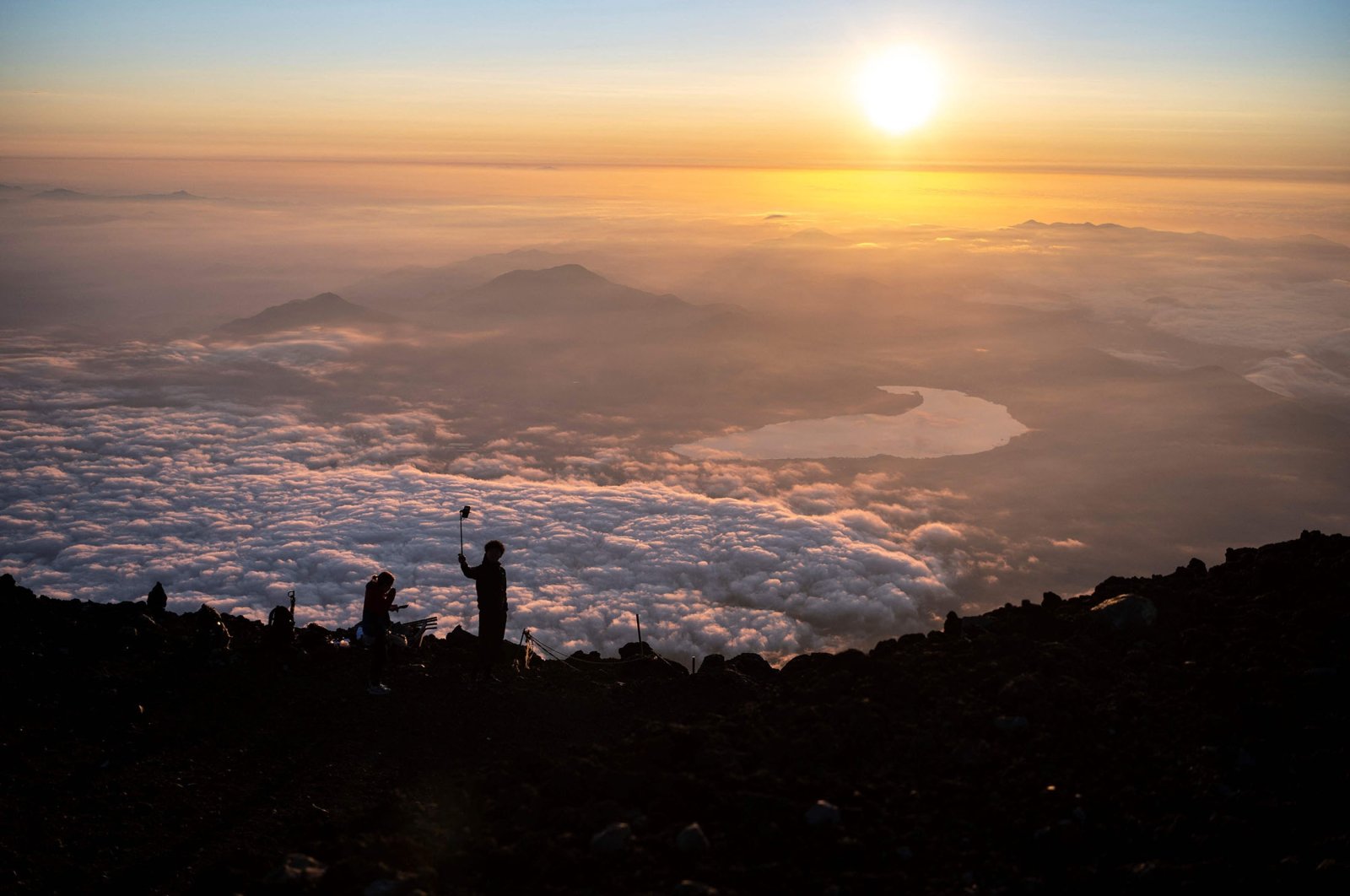 People watch the sunrise from the summit of Mount Fuji, some 70 kilometers (43 miles) west of the capital Tokyo, Japan, July 19, 2021. (AFP Photo)