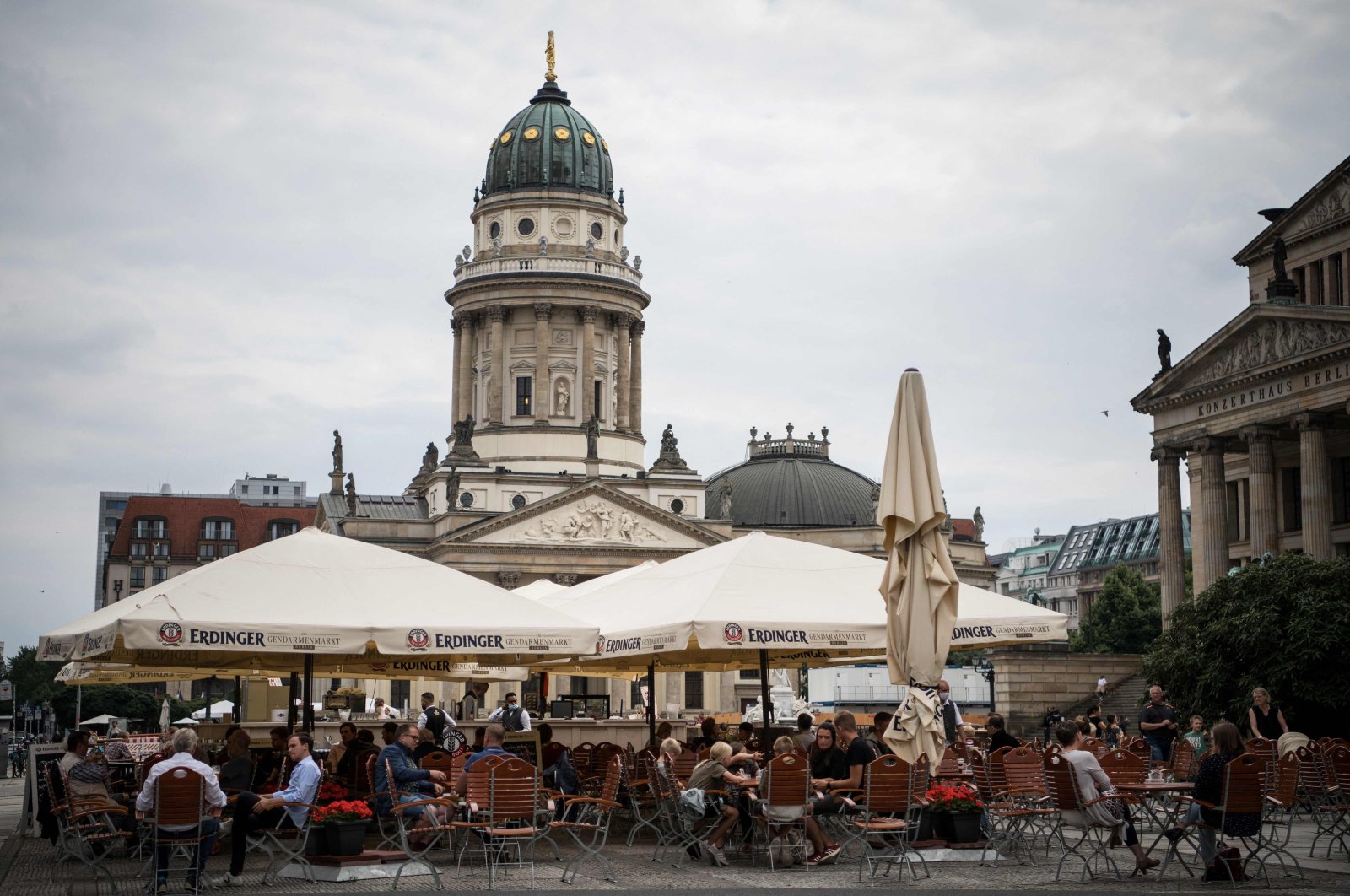 People sit outside in a restaurant at the Gendarmenmarkt in front of the New Church (Deutscher Dom) and the Konzerthaus concert hall in Berlin, Germany, July 22, 2021. (AFP Photo)