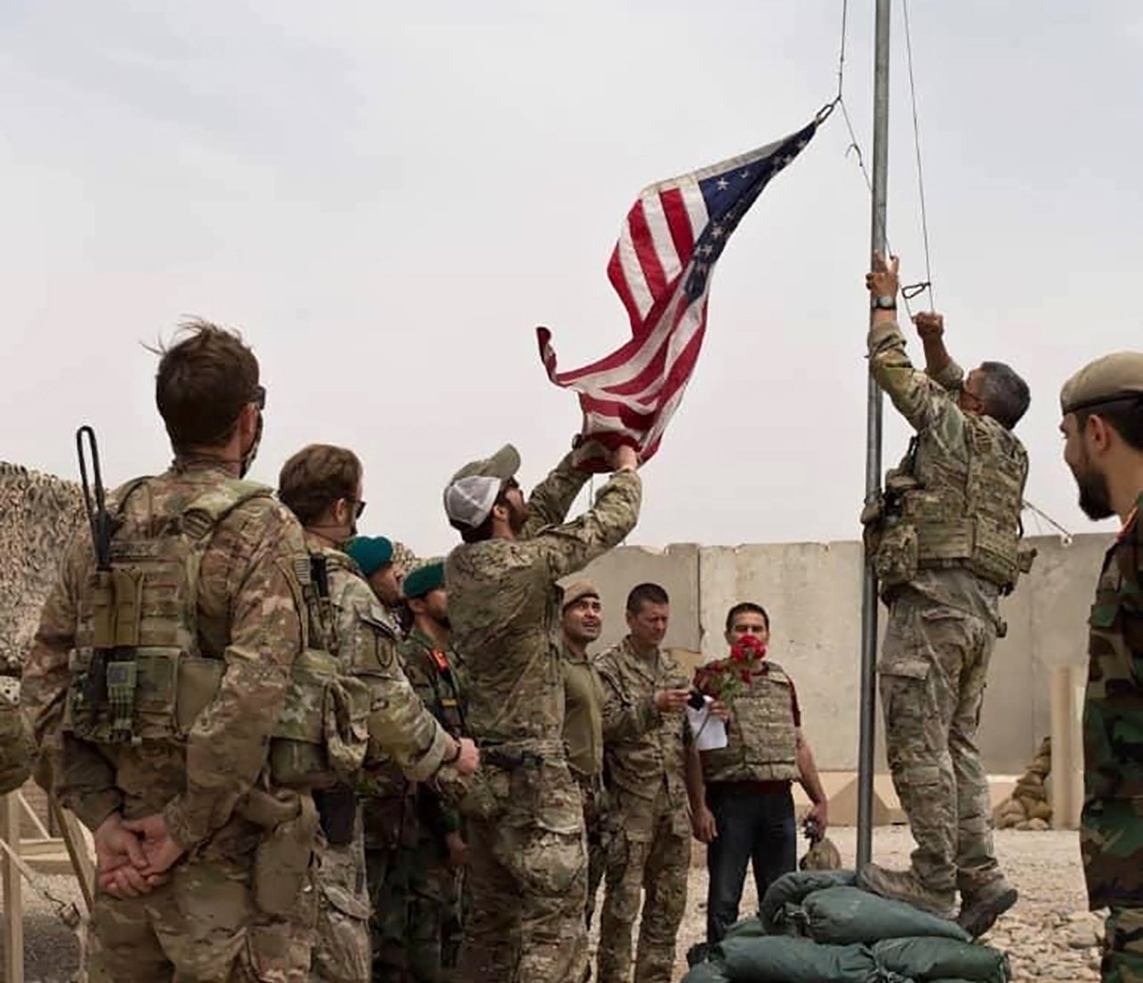 A U.S. flag is lowered as American and Afghan soldiers attend a handover ceremony from the U.S. Army to the Afghan National Army, at Camp Anthonic, in Helmand province, southern Afghanistan, May 2, 2021. (AP Photo)