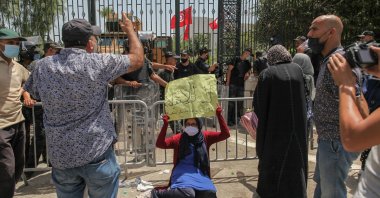 A female supporter of the conservative party Ennahdha raises a placard that reads in Arabic "No to the coup, tomorrow the people will be cut," as she sits on the ground during a sit-in protest led by the Tunisian Parliament Speaker Rached Ghannouchi, in front of the building of the Tunisian parliament in Bardo, in the capital Tunis, Tunisia, July 26, 2021. (Getty Images Photo)