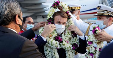 France's President Emmanuel Macron (C) is wrapped in garlands upon his arrival at Faa'a international airport for a visit to Tahiti in French Polynesia on July 24, 2021. (AFP Photo)