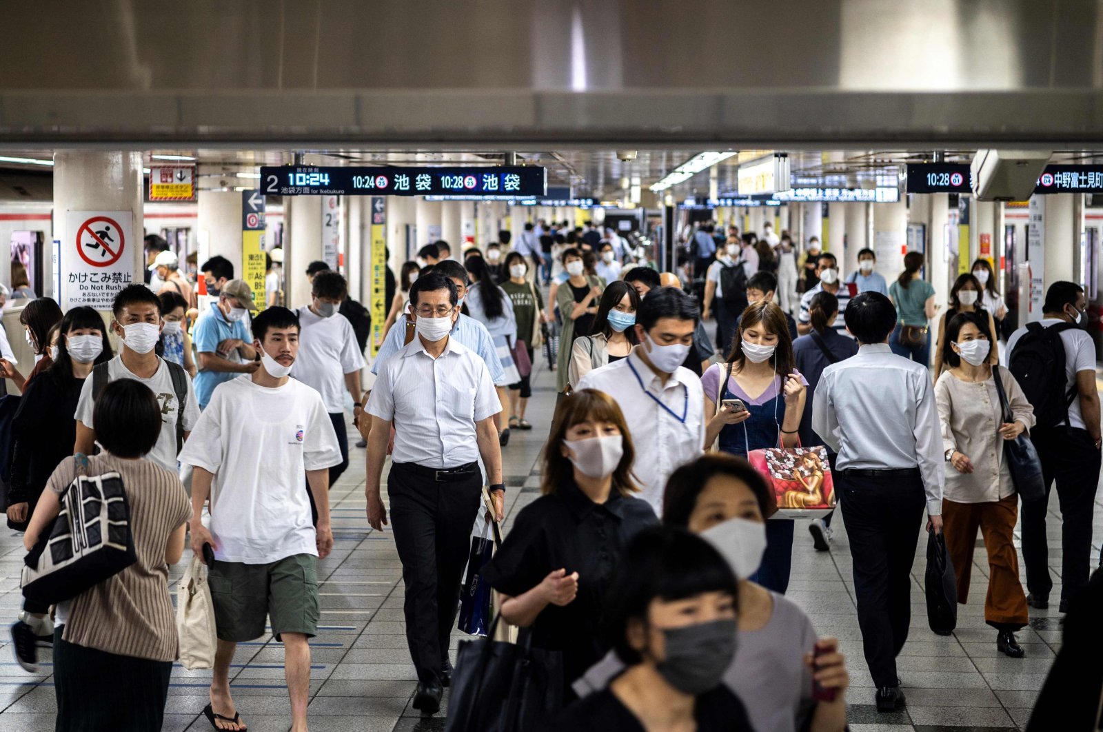 People walk in Tokyo's Shinjuku train station on July 20, 2021. (AFP Photo)