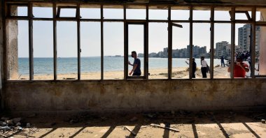 People walk on a beach inside an area fenced off by the Turkish military since 1974 in the abandoned coastal area of Varosha, a suburb of the town of Famagusta in the Turkish Republic of Northern Cyprus (TRNC), Oct. 8, 2020. (Reuters)