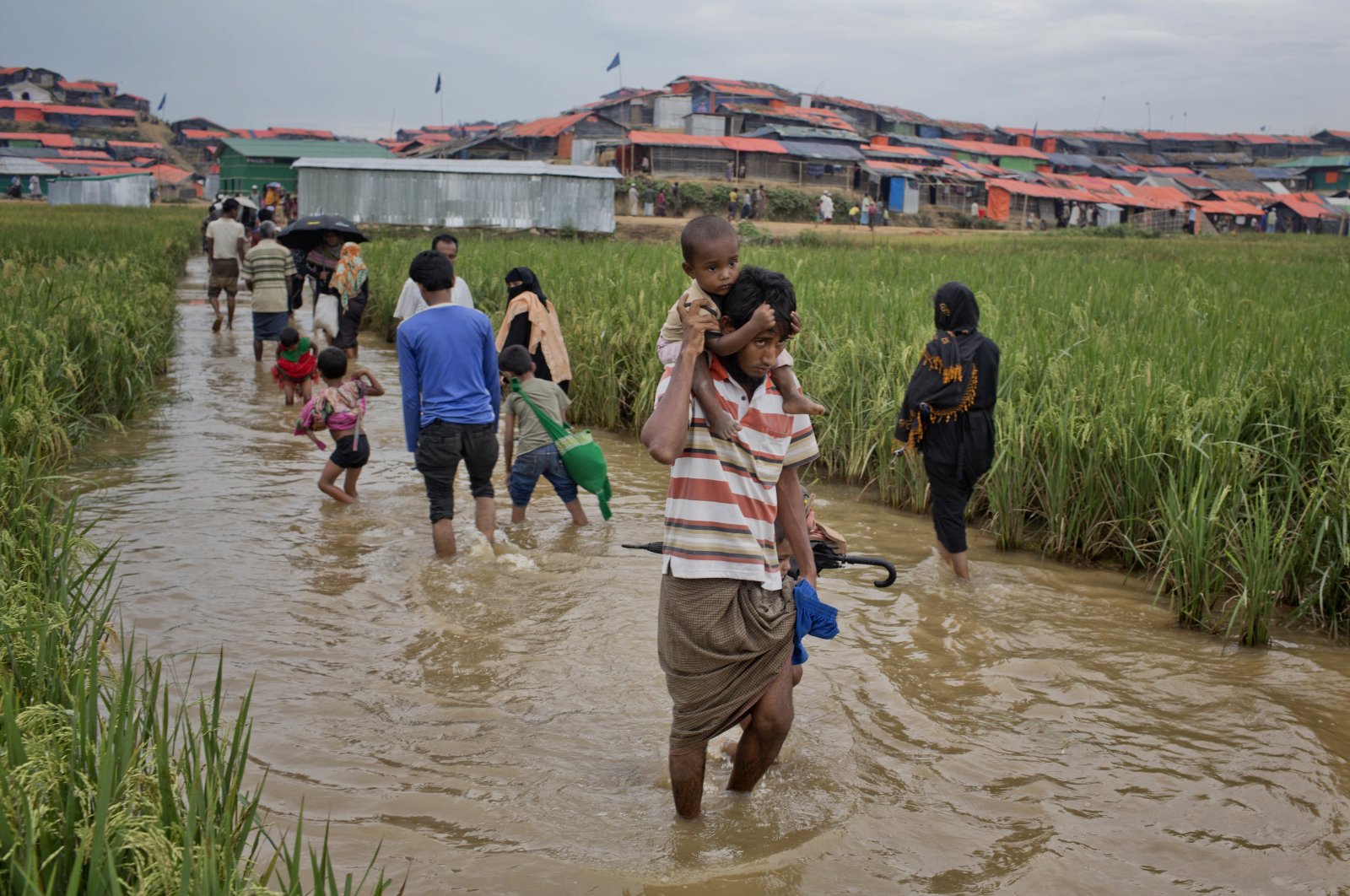 Rohingya Muslims, who crossed over from Myanmar into Bangladesh, wade past a waterlogged path leading to the Jamtoli refugee camp in Ukhiya, Bangladesh, Friday, Nov. 17, 2017. (AP Photo)