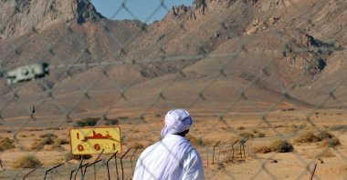 A man walks past a fence at the entrance of the former French nuclear bomb test site of Tena Fila mountain at Ain Ekra in Tamanrasset, 2,000 kilometers (1,242 miles) south of Algiers, Algeria, Feb. 25, 2010. (AFP Photo)