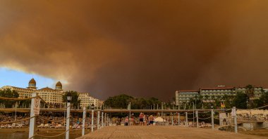 Dark smoke drifts over a hotel complex during a massive forest fire that engulfed a Mediterranean resort region on the southern coast near the town of Manavgat, Antalya, southern Turkey, July 29, 2021. (AFP Photo)