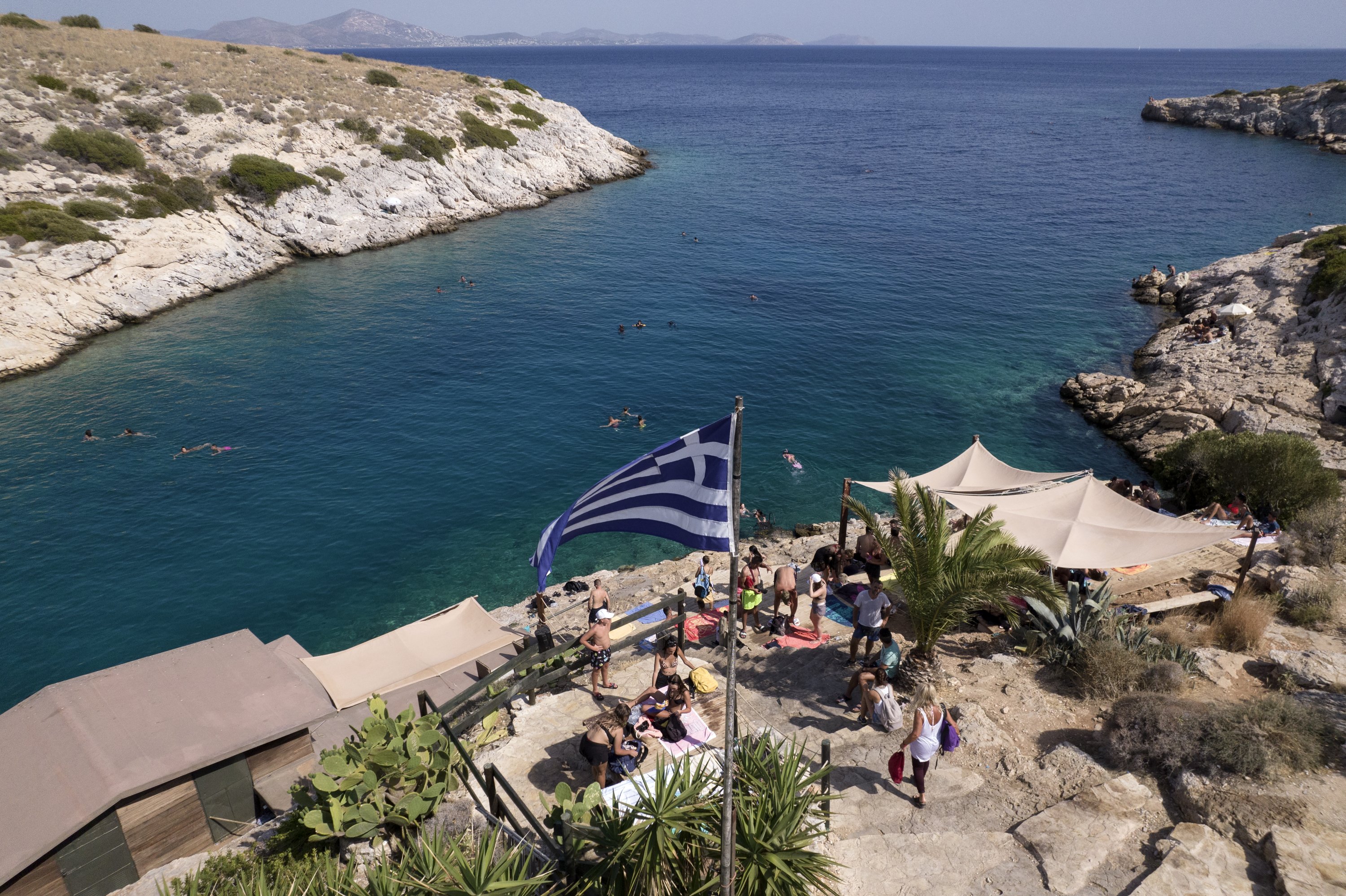 Οι άνθρωποι ποζάρουν δίπλα σε ένα beach bar στο προάστιο της Βουλιαγμένης, νοτιοδυτικά της Αθήνας, Ελλάδα, 29 Ιουλίου 2021 (Φωτογραφία AP)