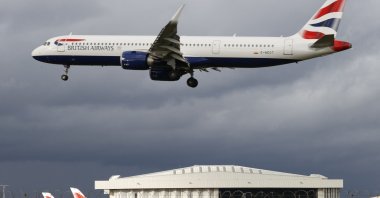 A British Airways aircraft flies over parked British Airways planes on the tarmac at London Heathrow Airport in west London, U.K., Feb. 5, 2021. (AFP Photo)