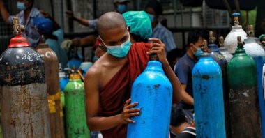 A Buddhist monk, wearing a face mask, holds an oxygen tank to refill outside the Naing oxygen factory at the South Dagon industrial zone in Yangon, Myanmar, July 28, 2021. (AP Photo)