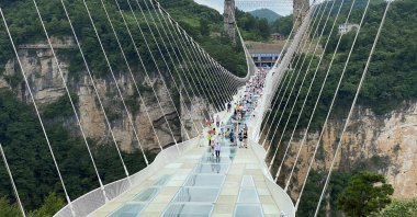 Visitors walk on a 430-meter (1,410-foot) long glass-bottomed bridge over the Zhangjiajie Grand Canyon in Zhangjiajie, Hunan province, China, July 8, 2021. (Reuters Photo)