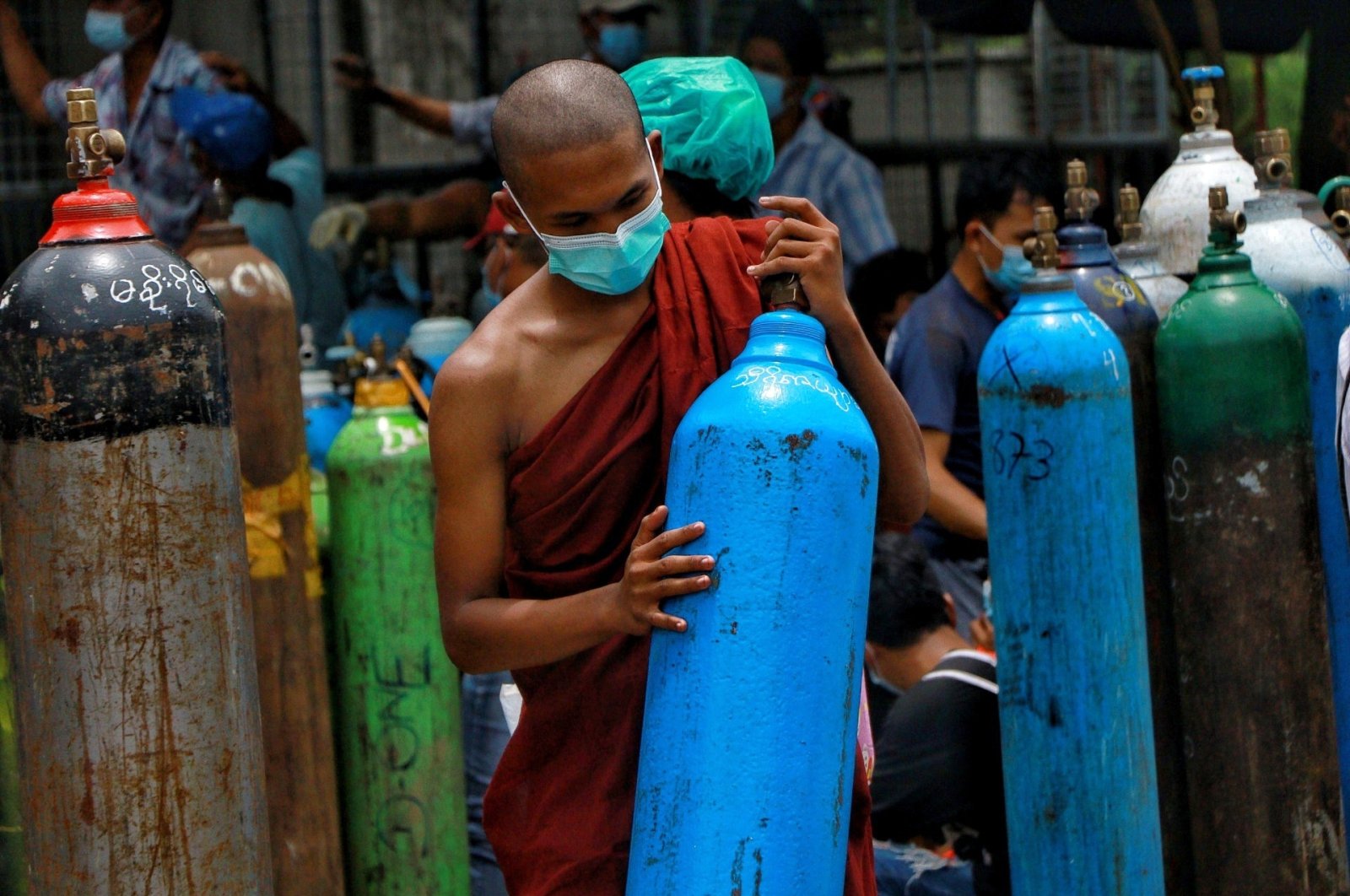 A Buddhist monk, wearing a face mask, holds an oxygen tank to refill outside the Naing oxygen factory at the South Dagon industrial zone in Yangon, Myanmar, July 28, 2021. (AP Photo)