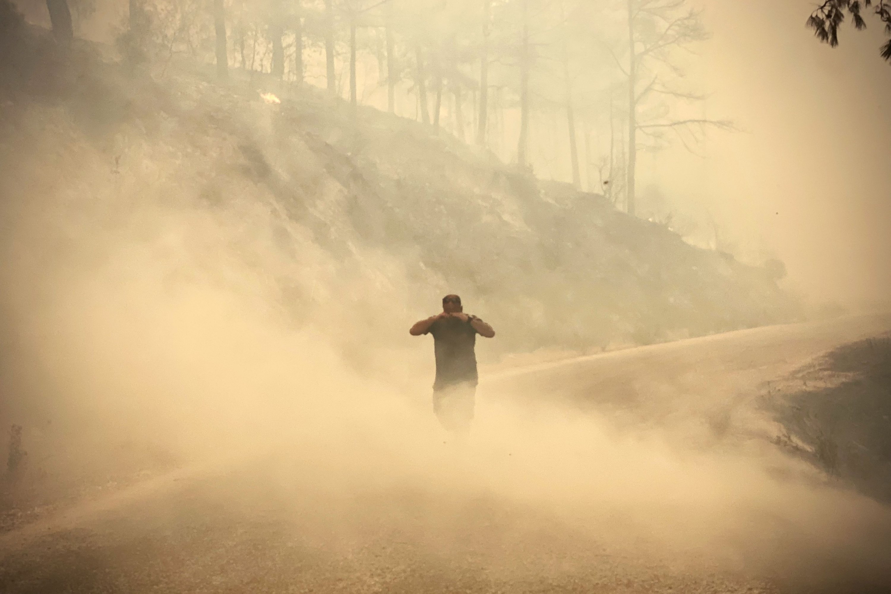 A pedestrian walks through the smoke as a massive wildfire engulfs a Mediterranean resort region on Turkey
