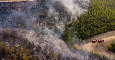 This aerial photograph shows firetrucks on a road as a wildfire engulfs a Mediterranean resort region on Turkey's southern coast near the town of Manavgat, on July 30, 2021.  (AFP Photo)