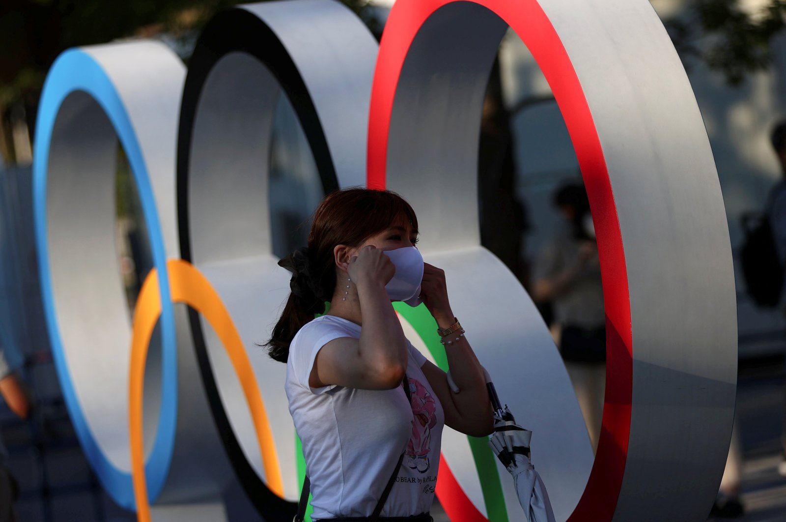 A woman adjusts her protective mask next to an Olympic rings monument outside the National Stadium, the main venue for the Tokyo 2020 Olympics amid the COVID-19 pandemic, Tokyo, Japan, July 31, 2021. (Reuters Photo)