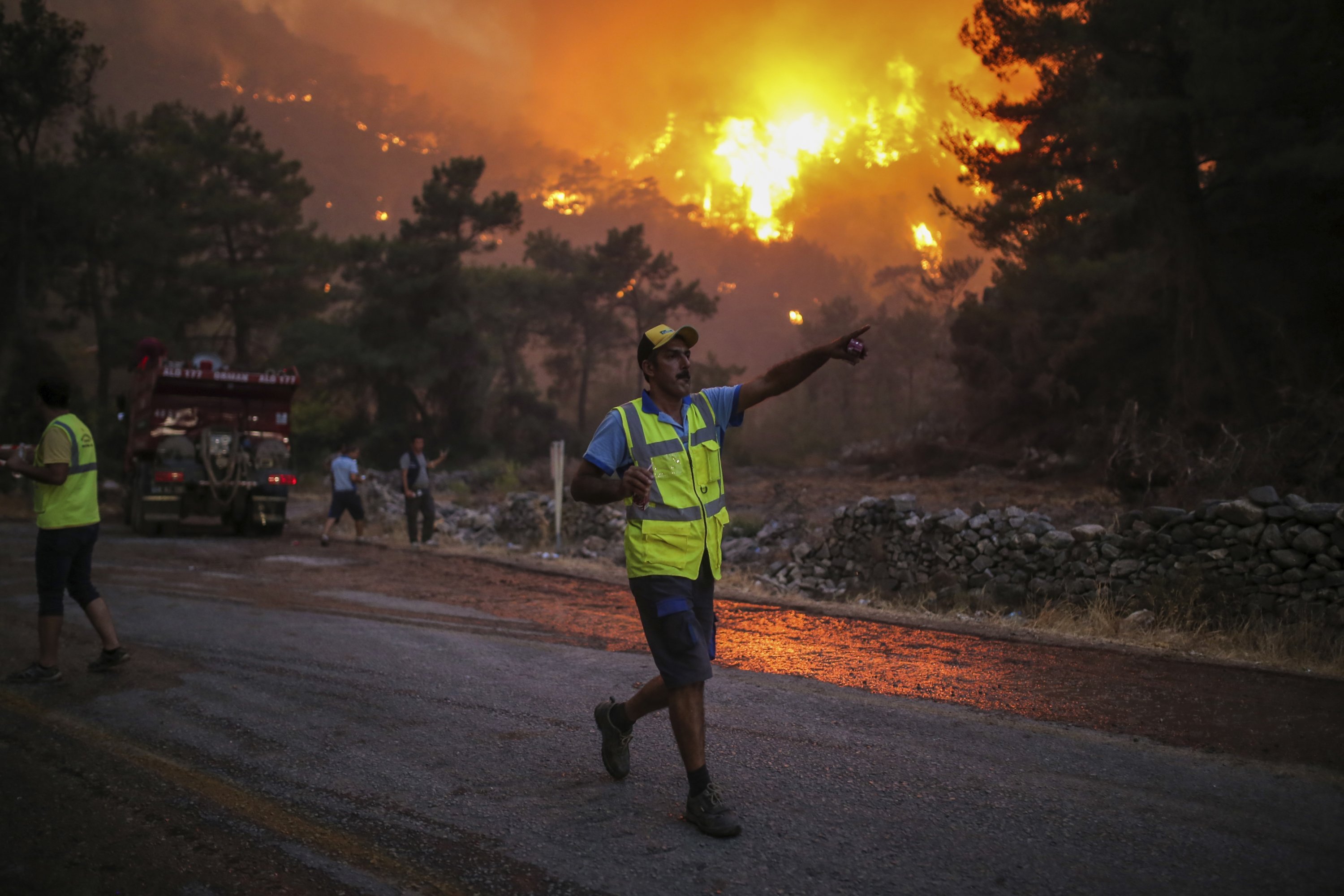 A firefighter points as he walks away from an advancing fire raging in Çökertme village, near Bodrum, Turkey, Aug. 2, 2021. (AP Photo)