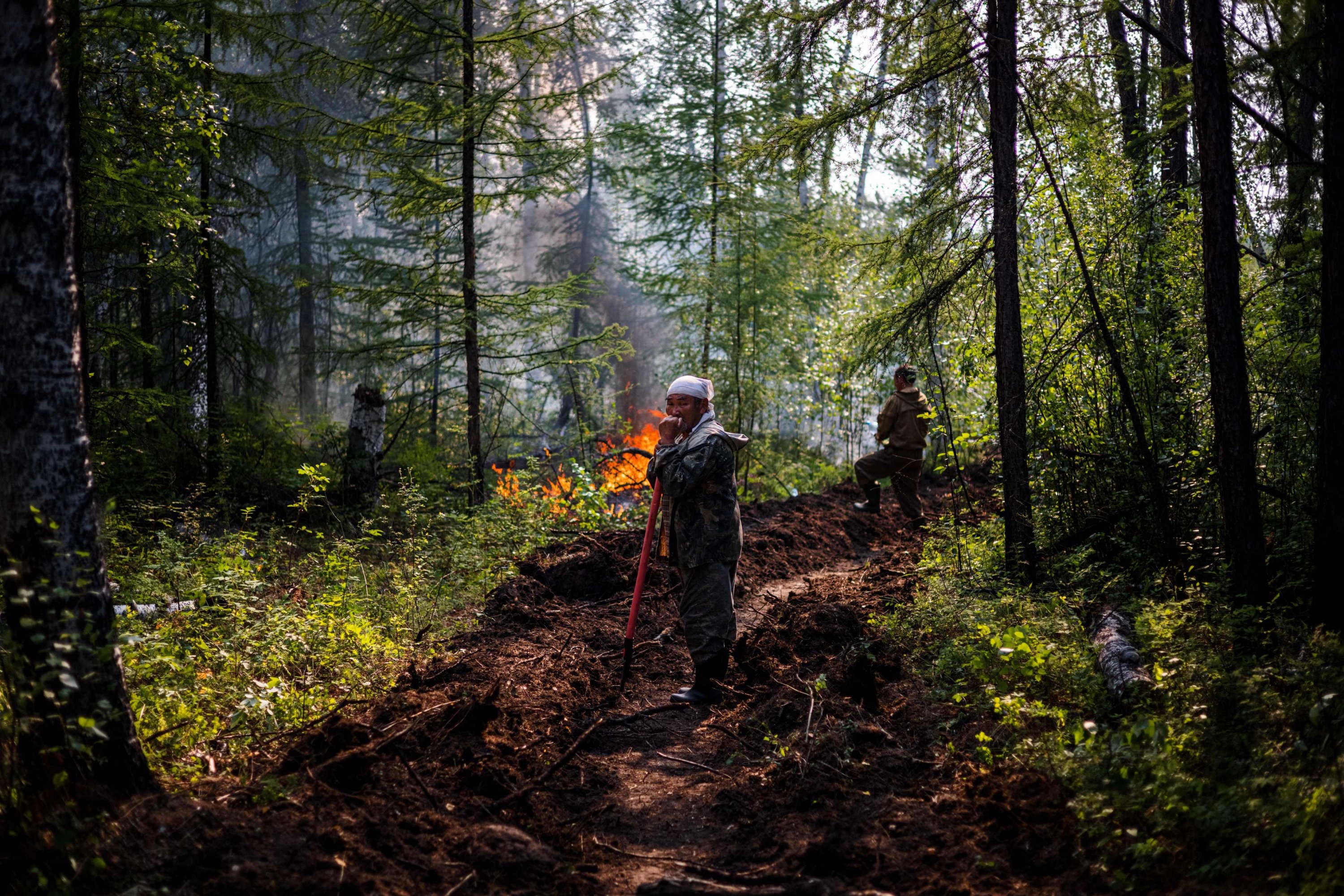  Ivan Fyodorov, 65, helps firefighters to control a five-kilometer long trench - that they dug with a tractor some days earlier - to prevent a wildfire from reaching their land in the Siberian region of Yakutia, at the edge of the village of Byas-Kyuel, on July 26, 2021.  (AFP Photo)