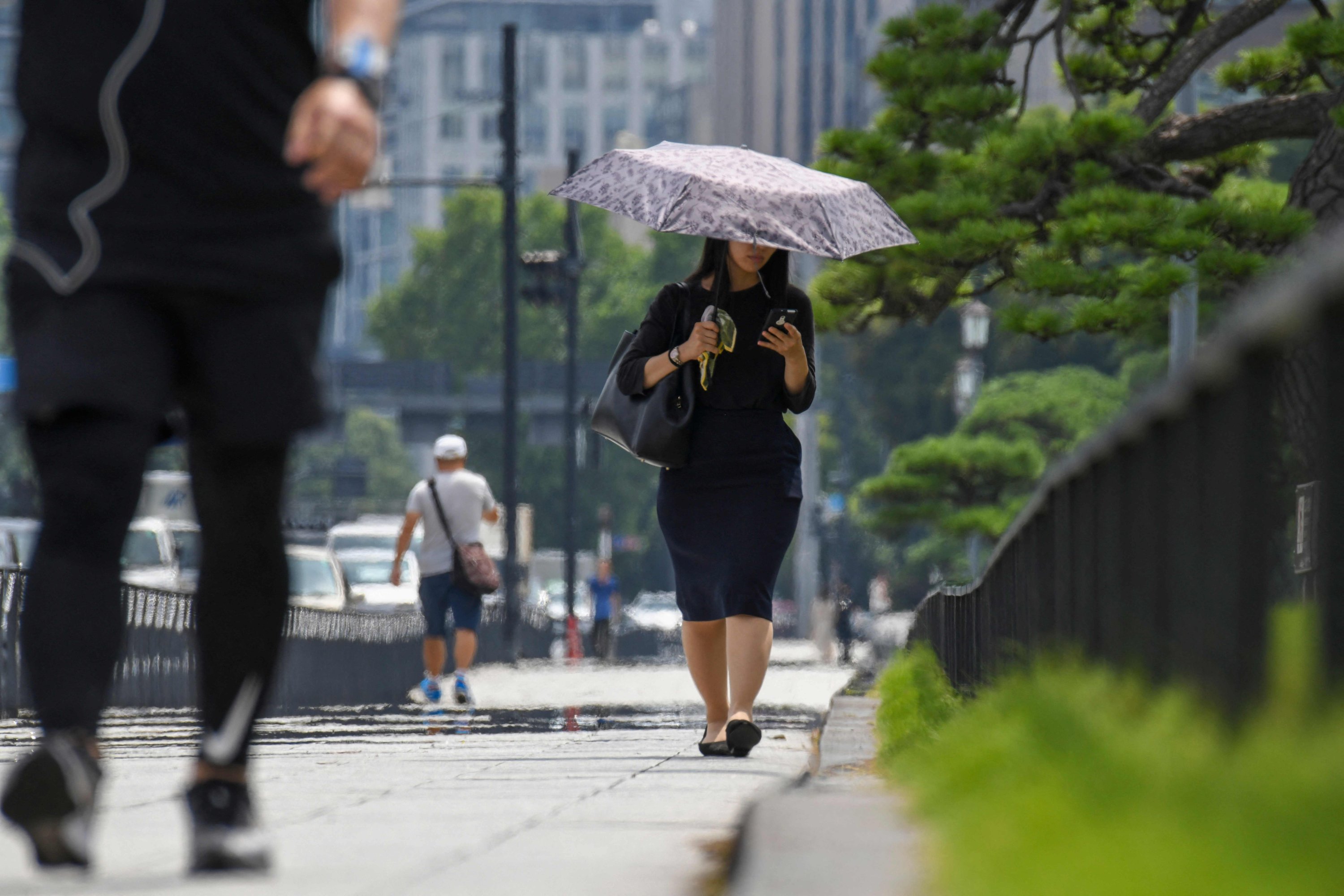 People walk on a sidewalk near the Imperial Palace during a heatwave in Tokyo on July 26, 2021. ( AFP Photo)