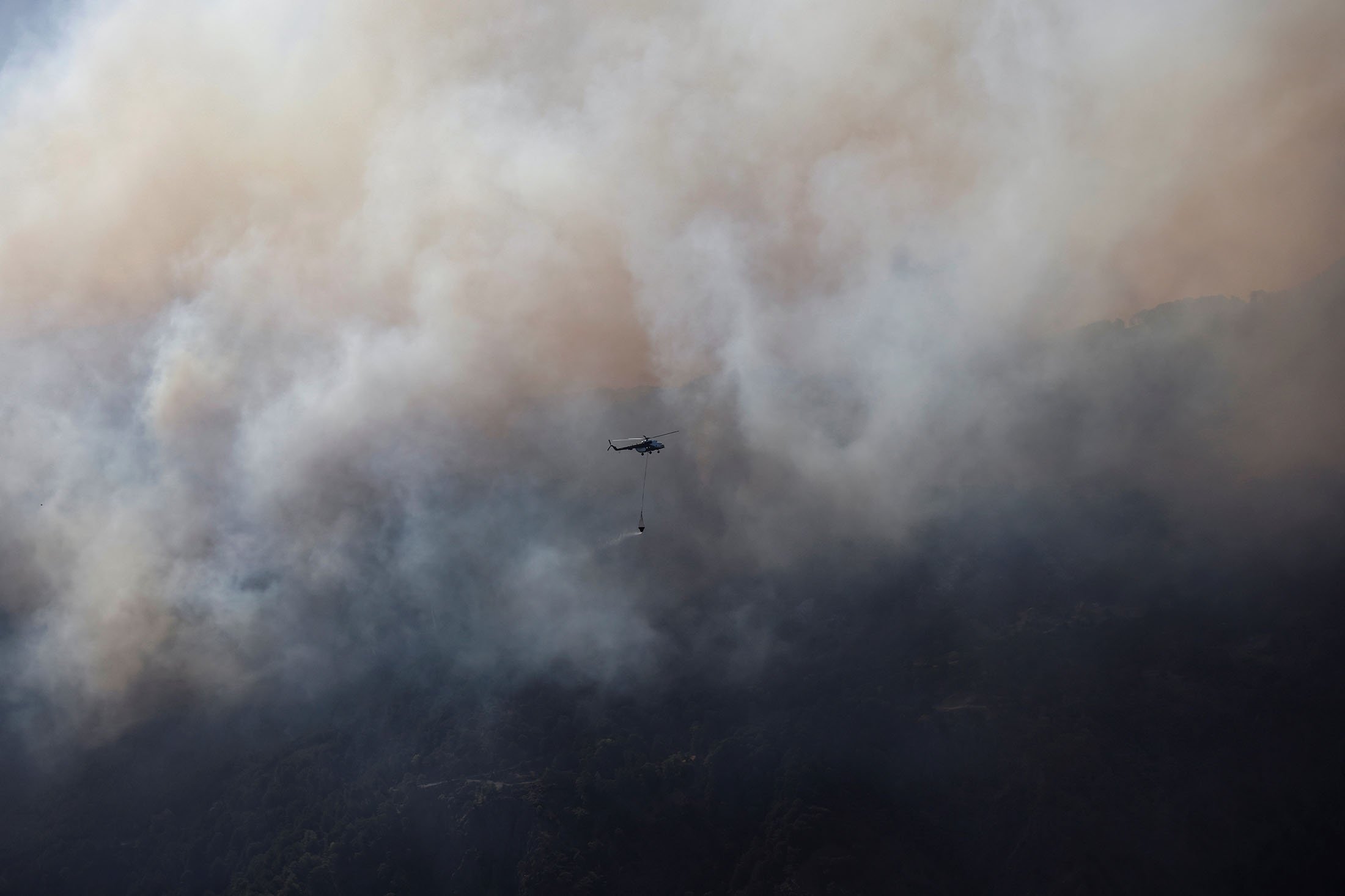 A firefighting helicopter carries water to drop during a wildfire near the Marmaris district of Muğla, Turkey, Aug. 3, 2021. (Reuters Photo)