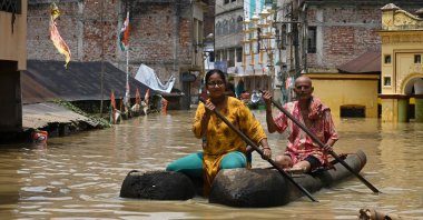 Residents ride a boat over a road submerged by floodwaters following heavy monsoon rains in Ghatal, around 100 kilometers (61 miles) from Kolkata, India, Aug. 2, 2021. (AFP Photo)