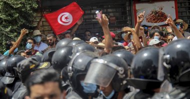 Protesters face Tunisian police officers during a demonstration in Tunis, Tunisia, Sunday, July 25, 2021. (AP Photo)