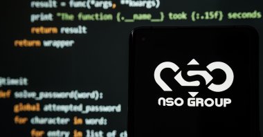 NSO Group logo seen on a smartphone placed in front of a laptop with a simple hacking code, Stafford, United Kingdom, July 19, 2021. (Shutterstock Photo)