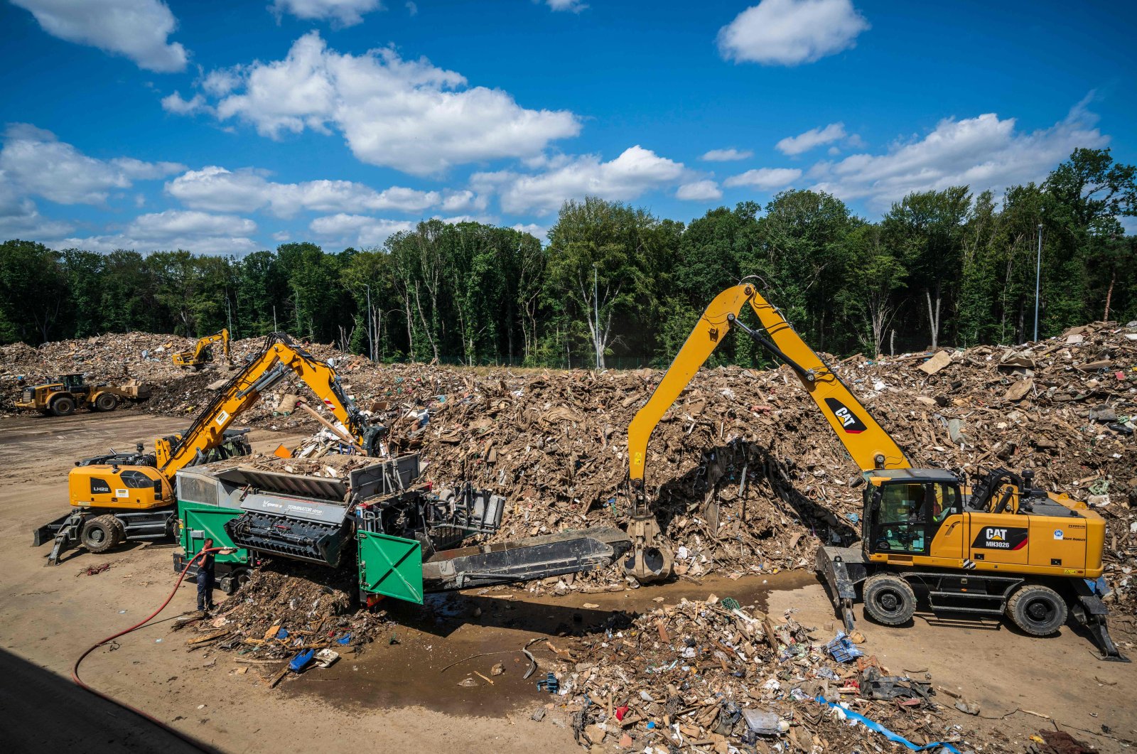 Front-end loaders move waste into a grinding container at the waste management center, an interim storage facility for bulky waste from the flooded regions in the Ahr Valley, in Niederzissen, North Rhine-Westphalia, western Germany, July 30, 2021. (AFP Photo)