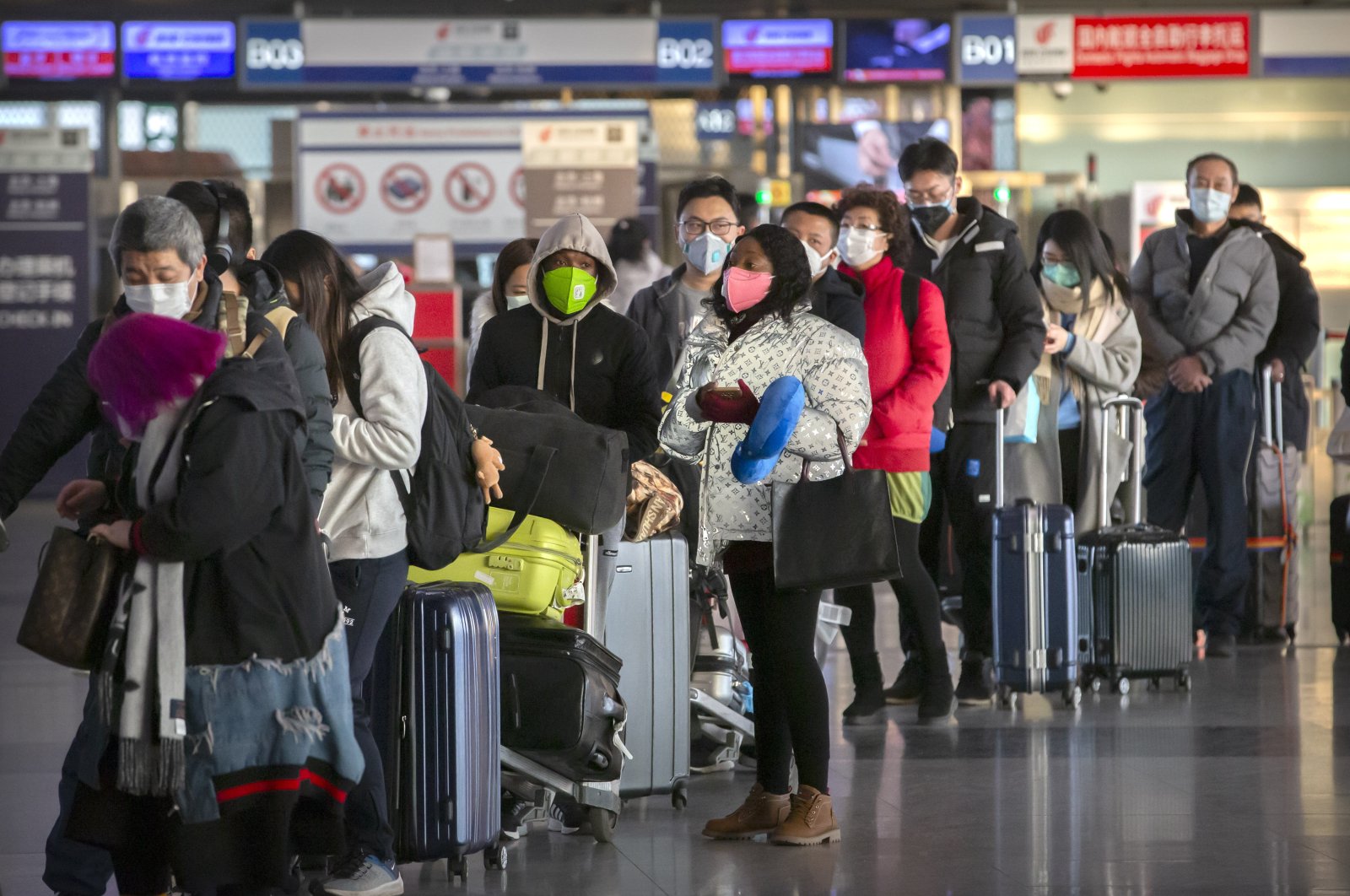 Travelers wearing face masks line up to check in for a flight at Beijing Capital International Airport in Beijing, China, Jan. 30, 2020. (AP Photo)