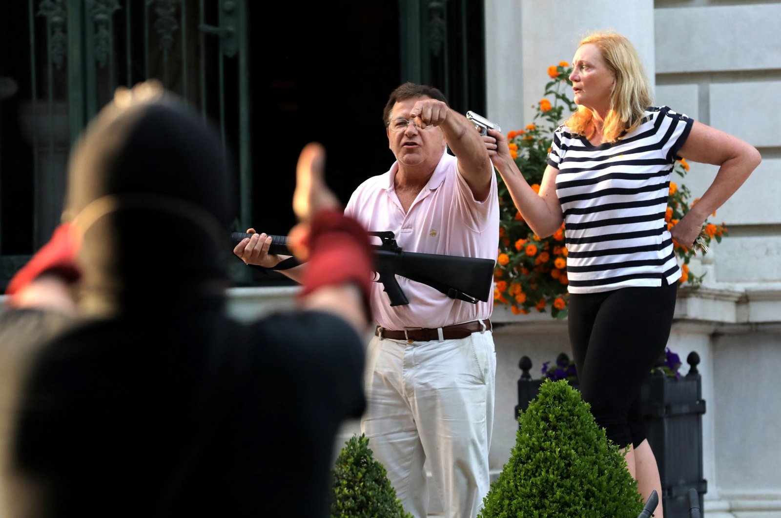 Armed homeowners Mark and Patricia McCloskey stand in front of their house as they confront peaceful protesters marching past their home to St. Louis Mayor Lyda Krewson's house, June 28, 2020, U.S. (Getty Images)