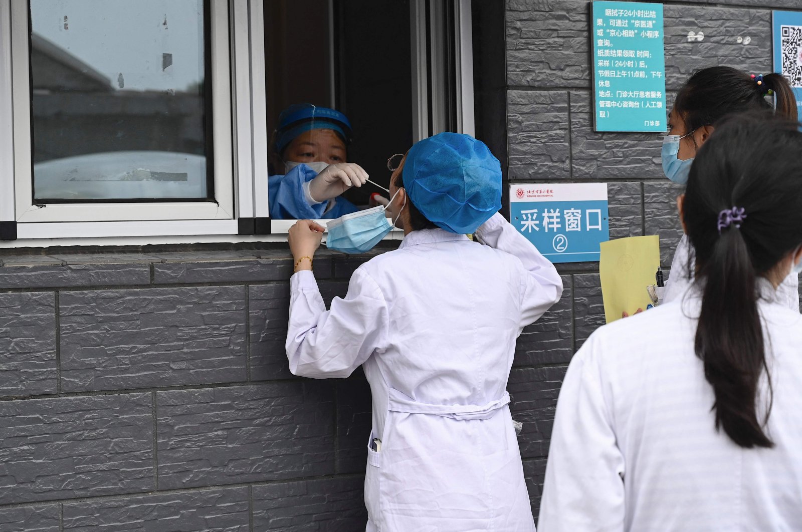 A health worker takes a swab sample from a medical worker to be tested for COVID-19 coronavirus at a hospital in Beijing, China, Aug. 3, 2021. (AFP Photo)