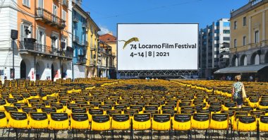 The large open-air screen and yellow chairs at the Piazza Grande square with old buildings in Lorcarno for the Annual International Film Festival, Switzerland, August 15, 2019. (Shutterstock Photo) 