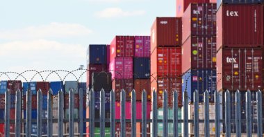 Freight shipping containers piled up high behind a fence topped with barbed wire in one of the U.K.'s busiest ports, Southampton, U.K., May 31, 2020. (Shutterstock Photo)